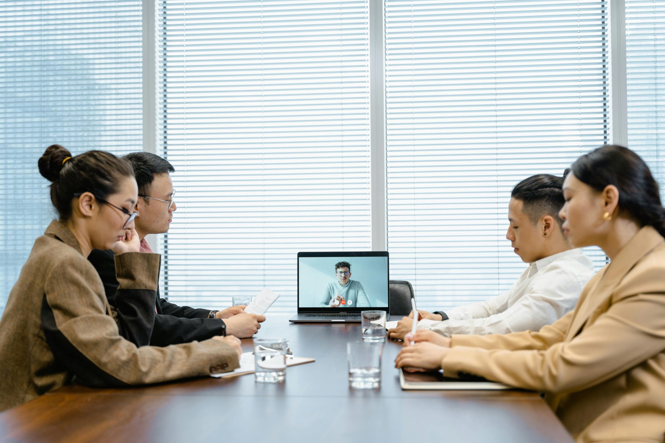 Professionals engage in a virtual business meeting around a conference table.